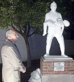 Néstor Abatidaga, uno de los impulsores del cuerpo de Bomberos, junto a la estatua que los homenajea.