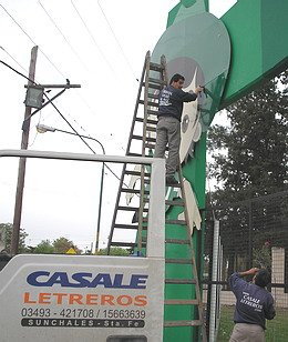 Operarios de la empresa Casale, ayer, durante la colocación de la gigantografía que identifica a la Fiesta.